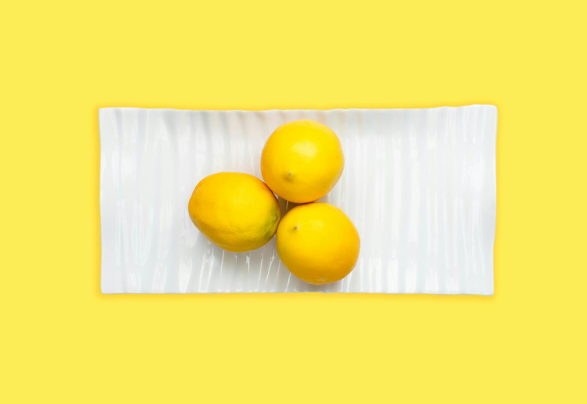 Mão segurando um vibrador de laranja em fundo roxo minimalista