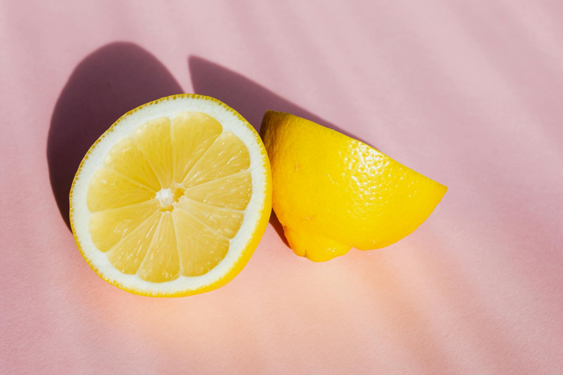 Halves de limão fresco e suculento em fundo rosa com raios solares
