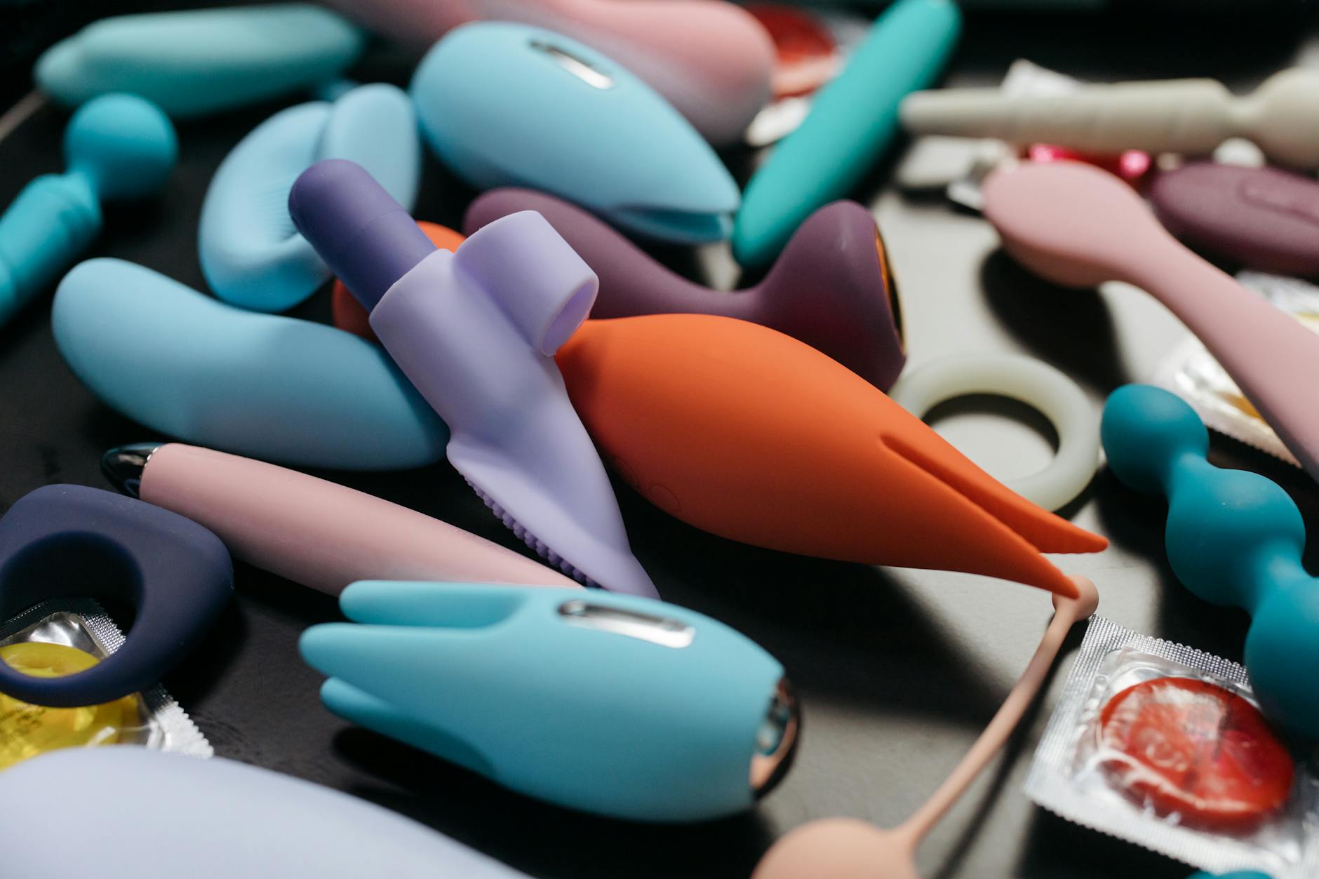 Woman holding blue and pink silicone vibrators in a thoughtful pose