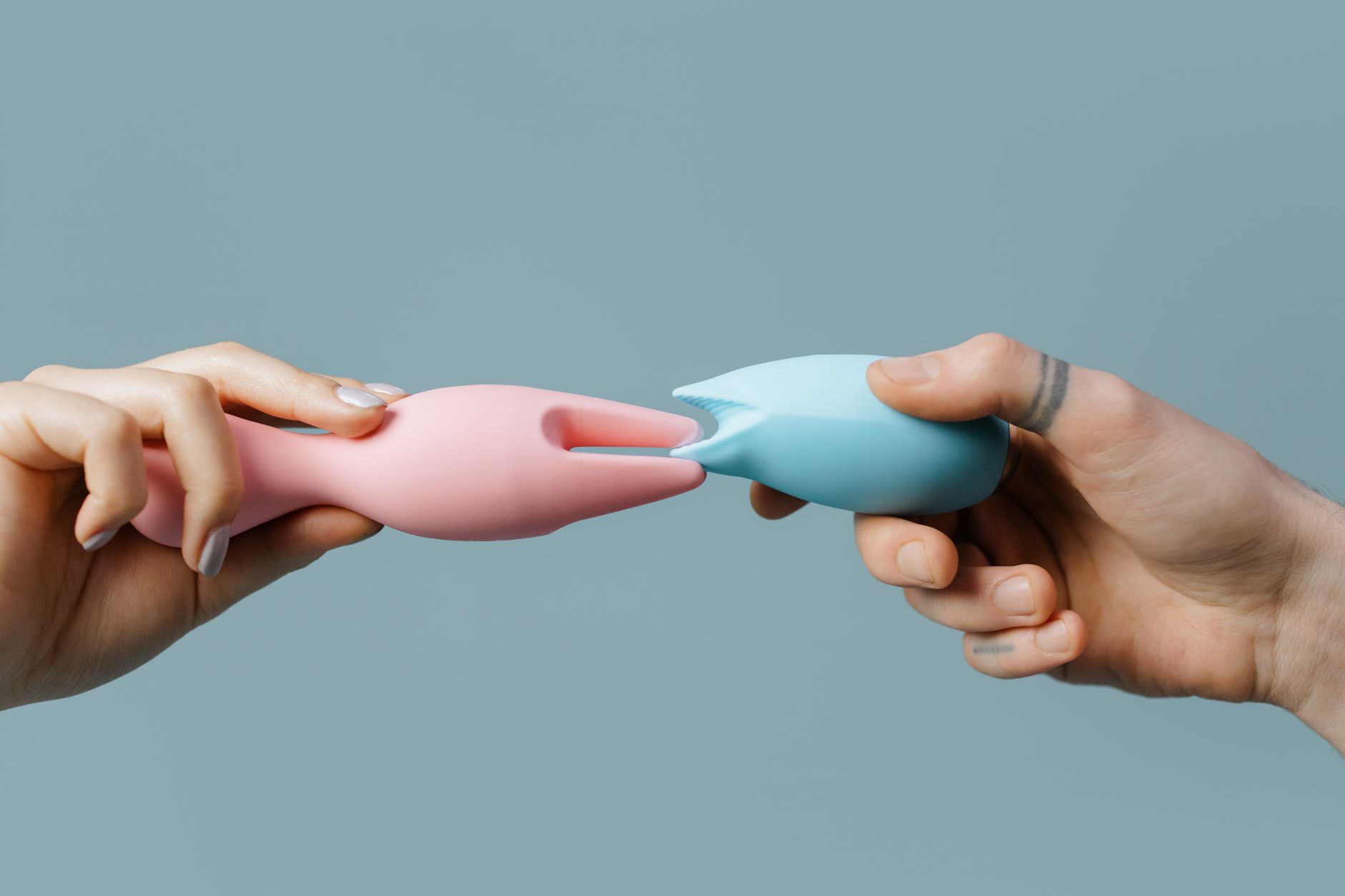 Mãos segurando brinquedos de silicone pastel em contexto de estilo de vida.