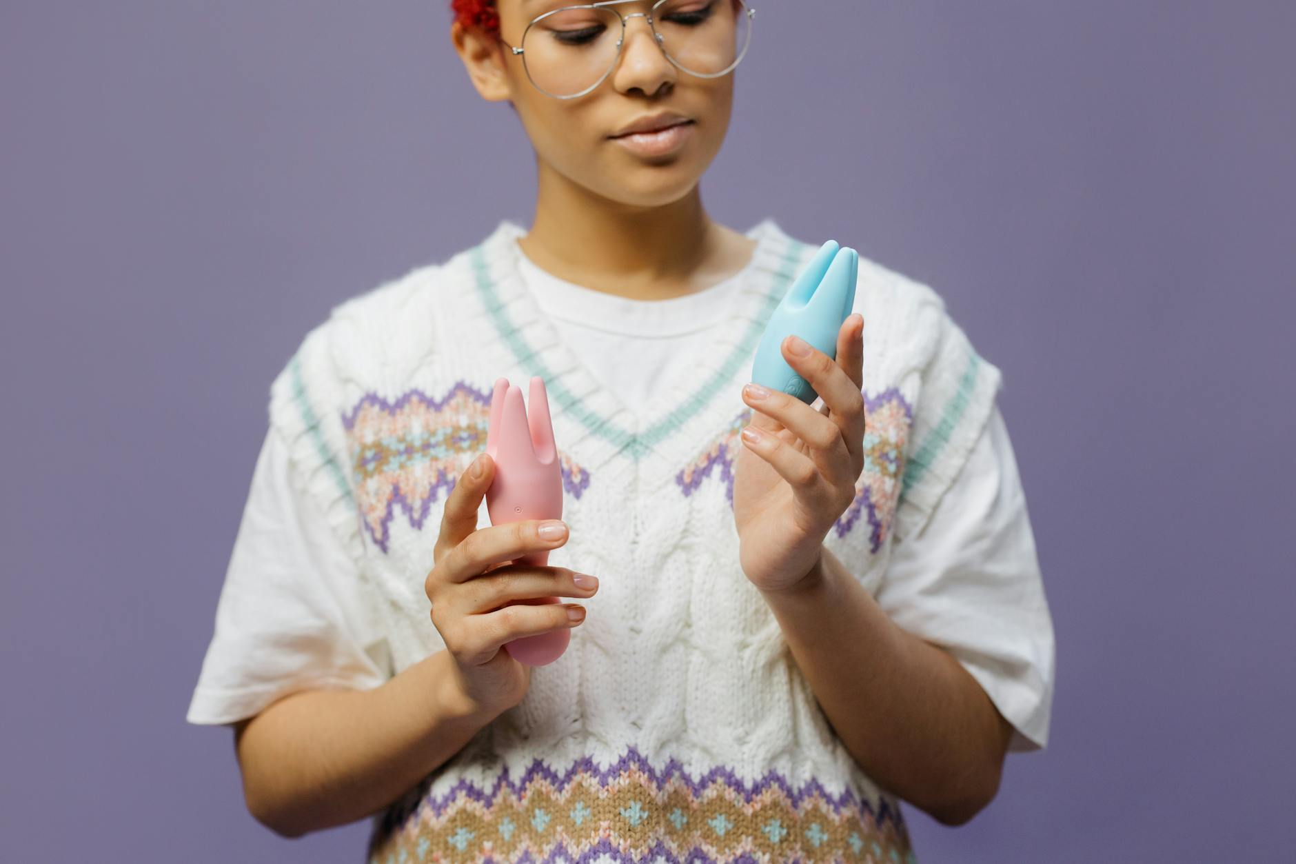 Mulher contemplativa segurando vibradores de silicone azul e rosa, representando autoconhecimento e prazer durante períodos de estresse